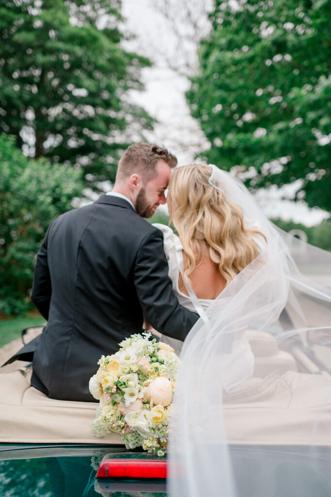 bride and groom ride away in vintage car