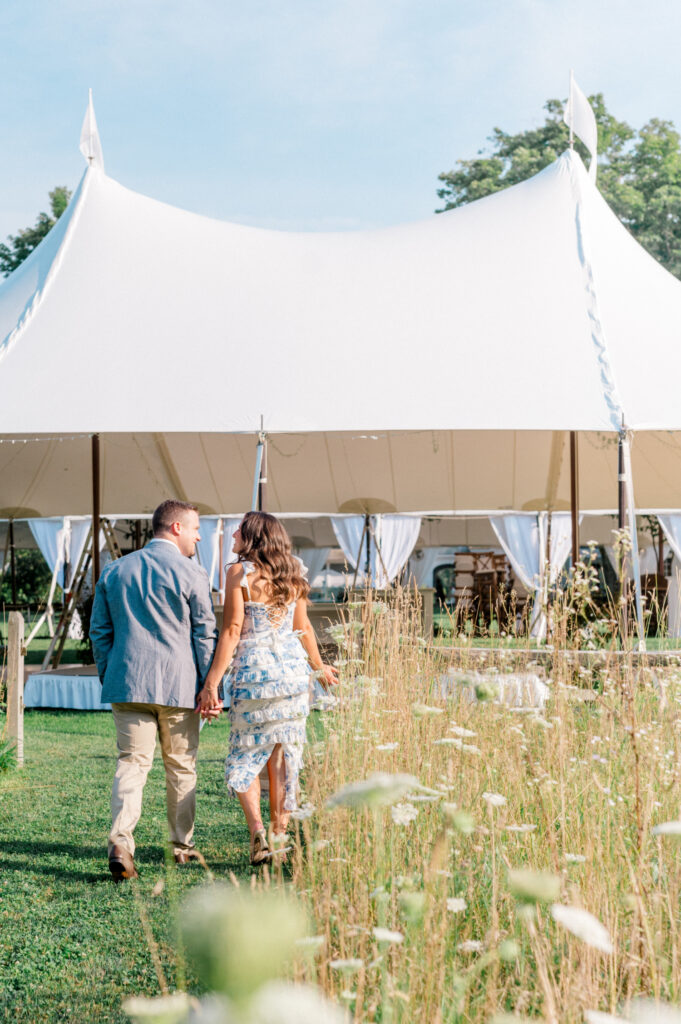 bride and groom walking into outdoor tented wedding welcome party