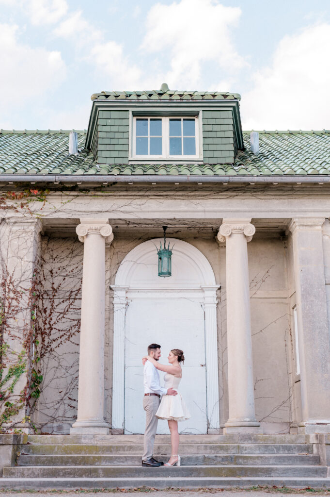 Bride and groom embracing on the steps of Eolia Mansion, one of the best wedding venues in Connecticut, framed by classical columns and a green-tiled roof.