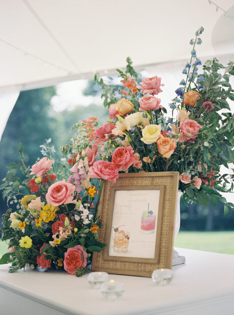 A vibrant arrangement of colorful flowers in pink, yellow, and orange shades displayed on reception bar, captured on film for a timeless and romantic feel.