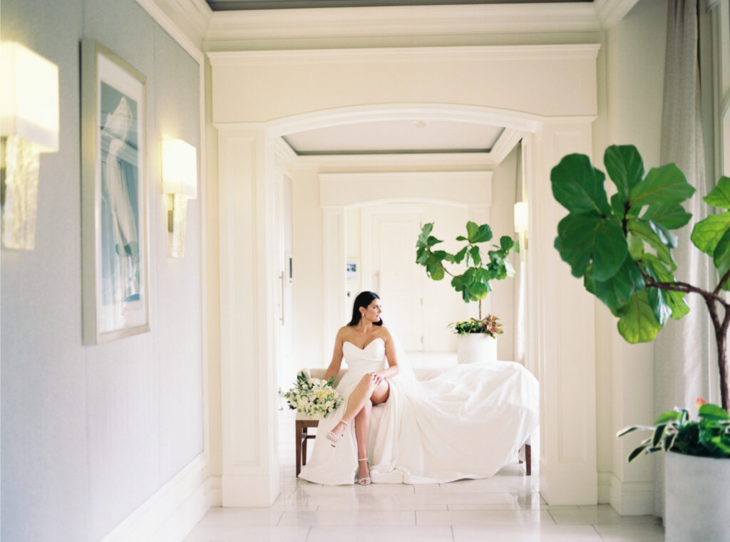 Film photo of bridal portrait as bride sits on cream couch looking out the window. 