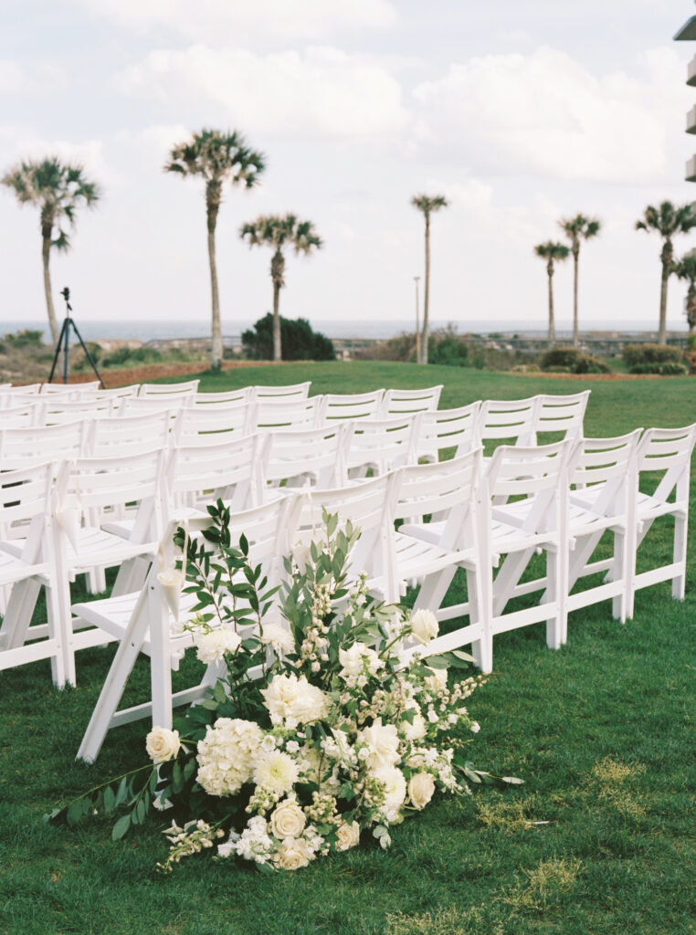 Film photo of monochromatic white floral arrangement at base of aisle for wedding ceremony. 