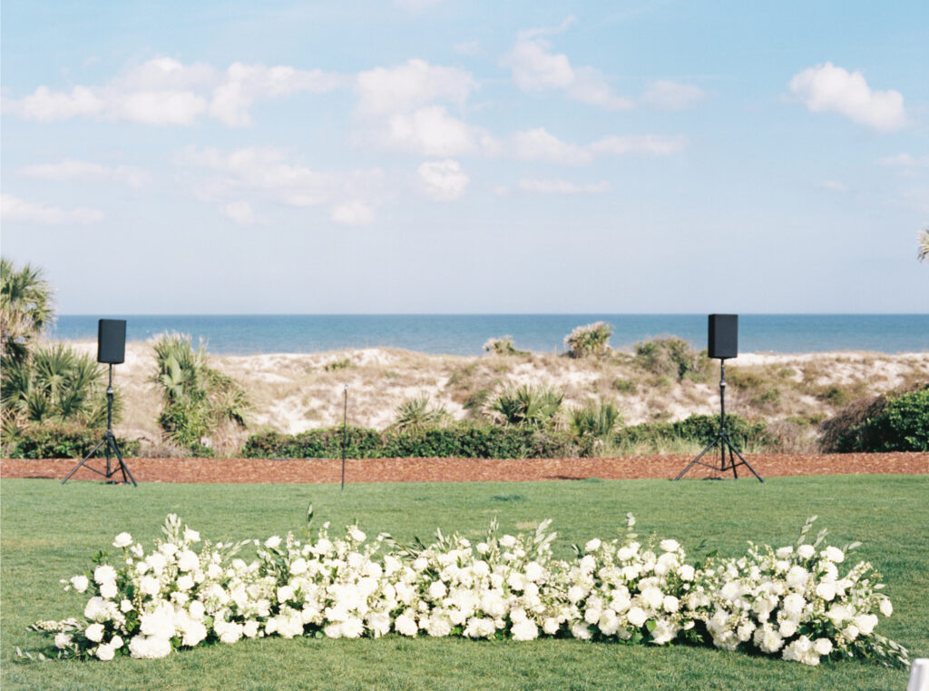 Film photo of monochromatic white floral ground-level arch for wedding ceremony. 