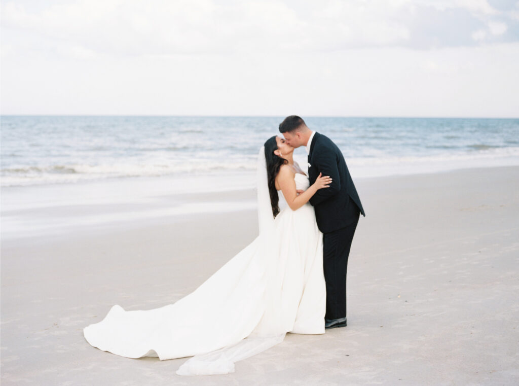 Film photo of bride and groom kissing on the beach. 