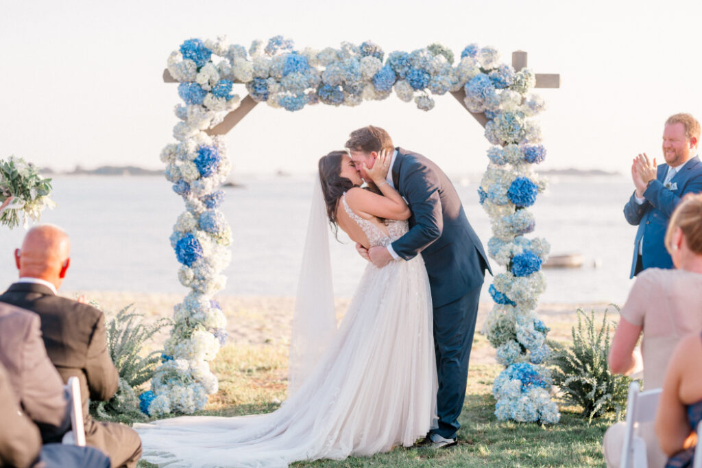 couples first kiss at outdoor wedding ceremony by the water at the point at norwalk cove