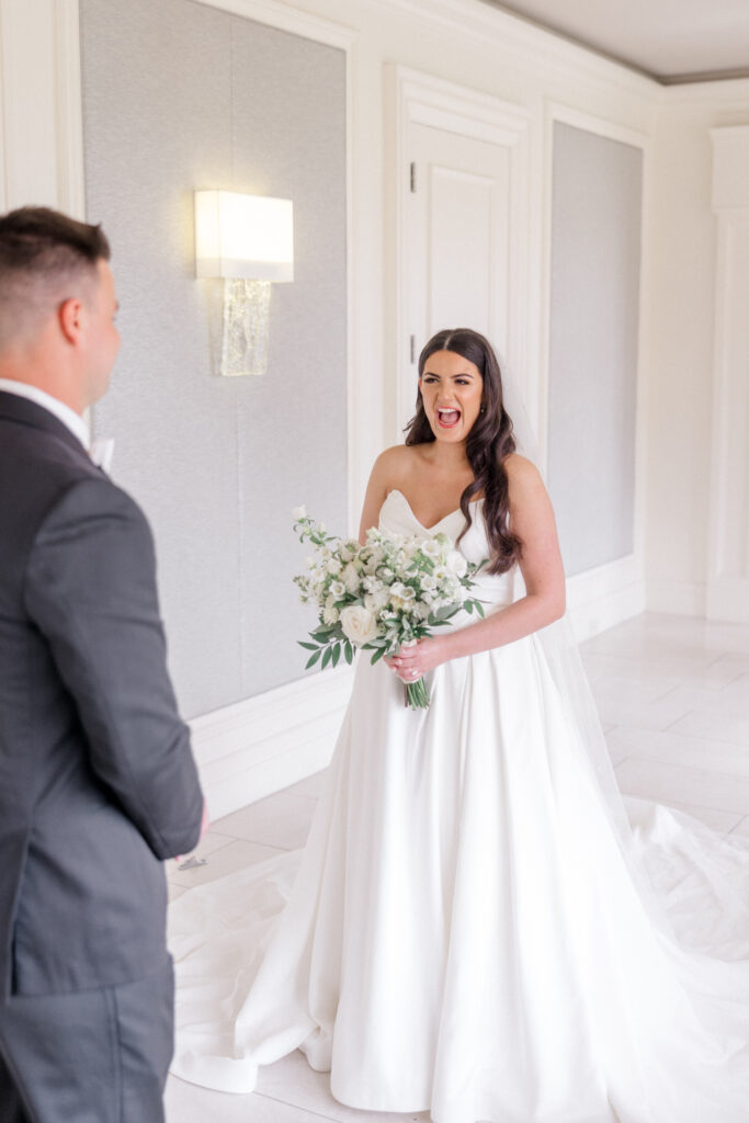 Bride stands excited as her husband turns around to see her for the first time on their wedding day. 