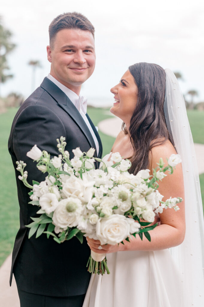 Bride smiles and laughs as she looks at groom. Groom smiles and looks into camera. 