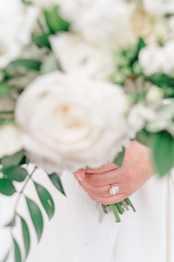 Close of of brides hand with engagement ring as she hold her bouquet. 