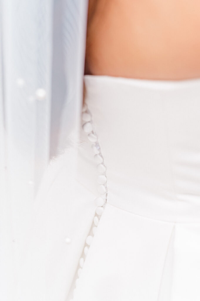 Detail shot of the back of brides dress, highlighting the intricate buttons and pearls of the veil. 