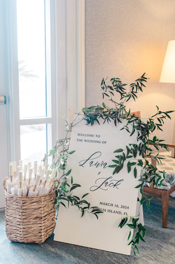 White wedding welcome sign surrounded with greenery. 