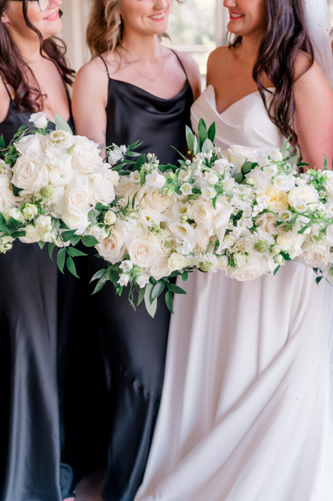 Close up of bridesmaids and bride standing and holding their bouquets closely together. 