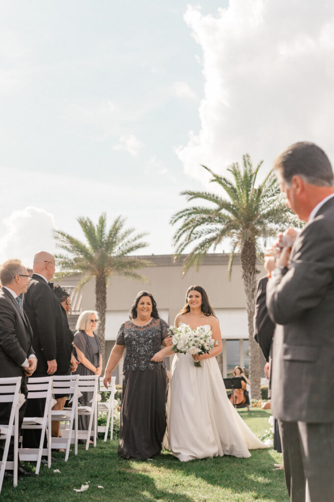 Bride walks with her mother down the aisle. 