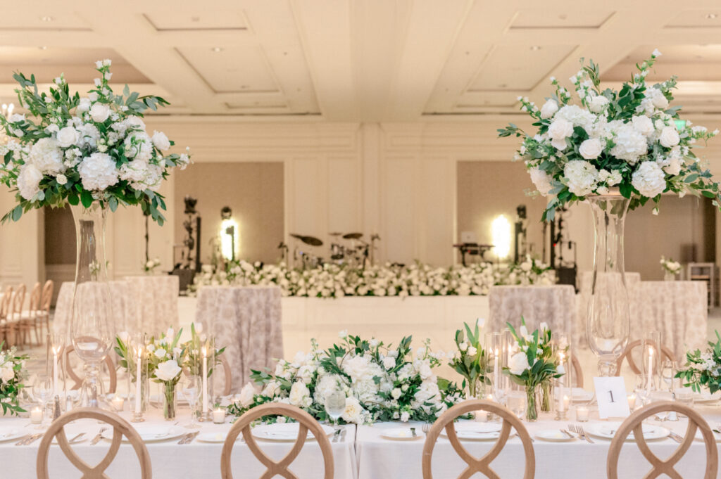 Timeless, monochromatic white floral arrangements in tall vases with greenery. 