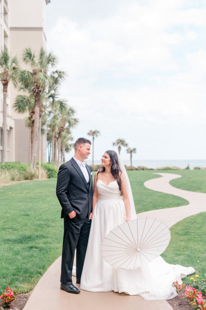 Bride and grooms stand together holding hands and smiling before their ceremony. 