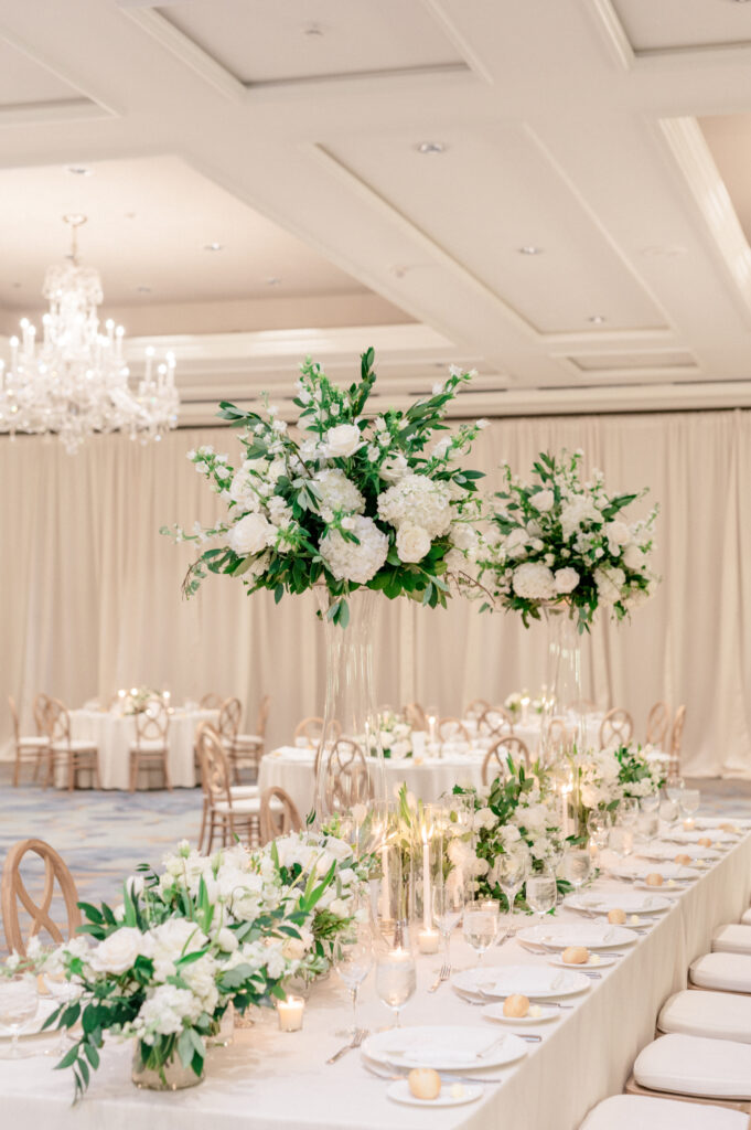 Timeless, monochromatic white floral arrangements in tall vases with greenery. 