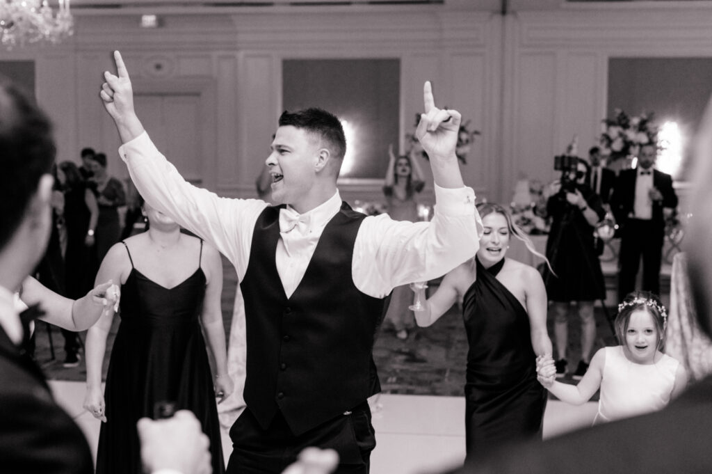 Black and white photo of groom ecstatic as he dances during wedding reception. 