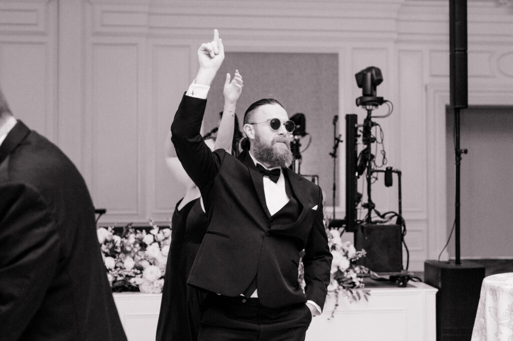 Black and white photo of guest dancing at wedding reception. 