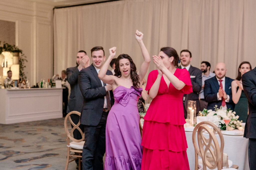 Guests at reception tables dancing as the newly wed couple makes their grand entrance. 