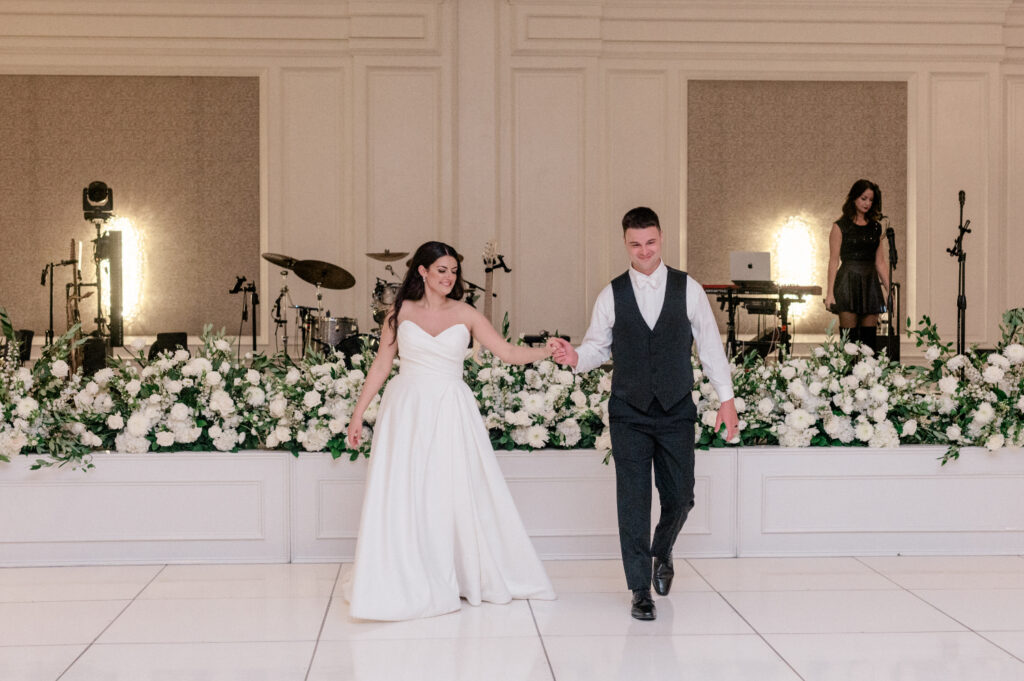 Bride and groom walk onto white tile dance floor to share first dance. 