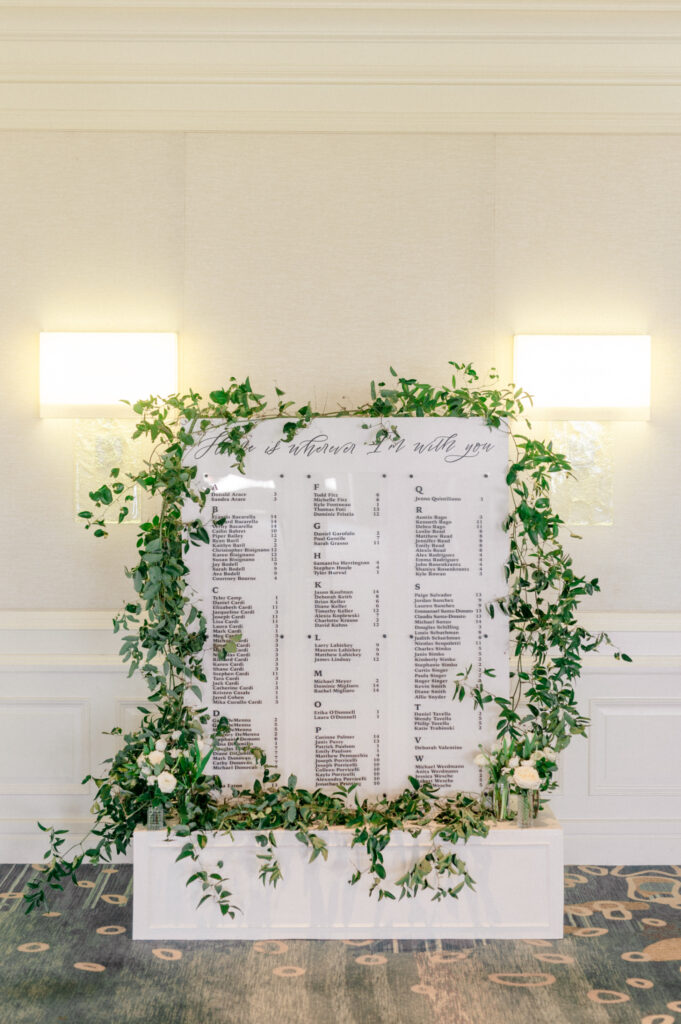 Large white seating chart surrounded by greenery. 