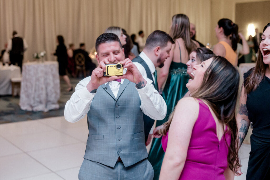 Guests on dance floor taking pictures with film camera. 