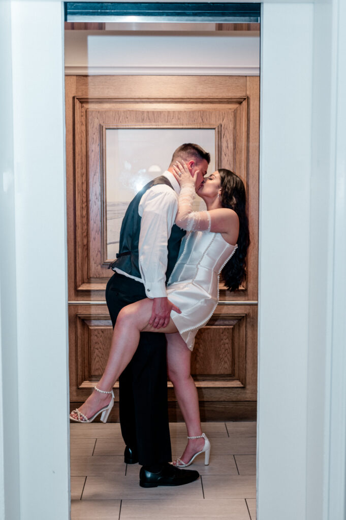 Bride and groom kissing in elevator as the doors close. 