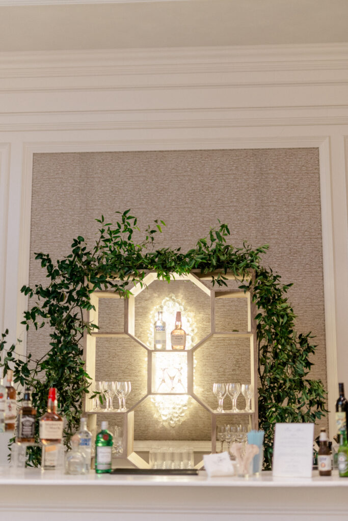 Wedding reception bar decorated with soft lights and greenery. 