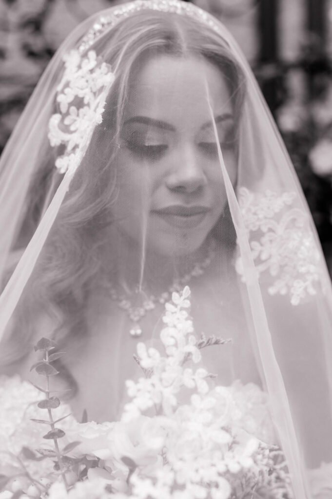  A timeless black-and-white bridal portrait of a bride gazing softly through her lace-edged veil.