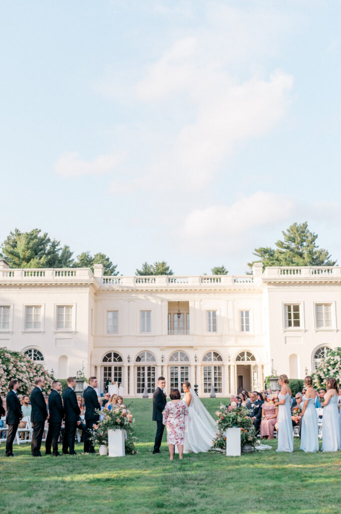 An outdoor wedding ceremony on the Wadsworth Mansion lawn with a bride and groom exchanging vows. 