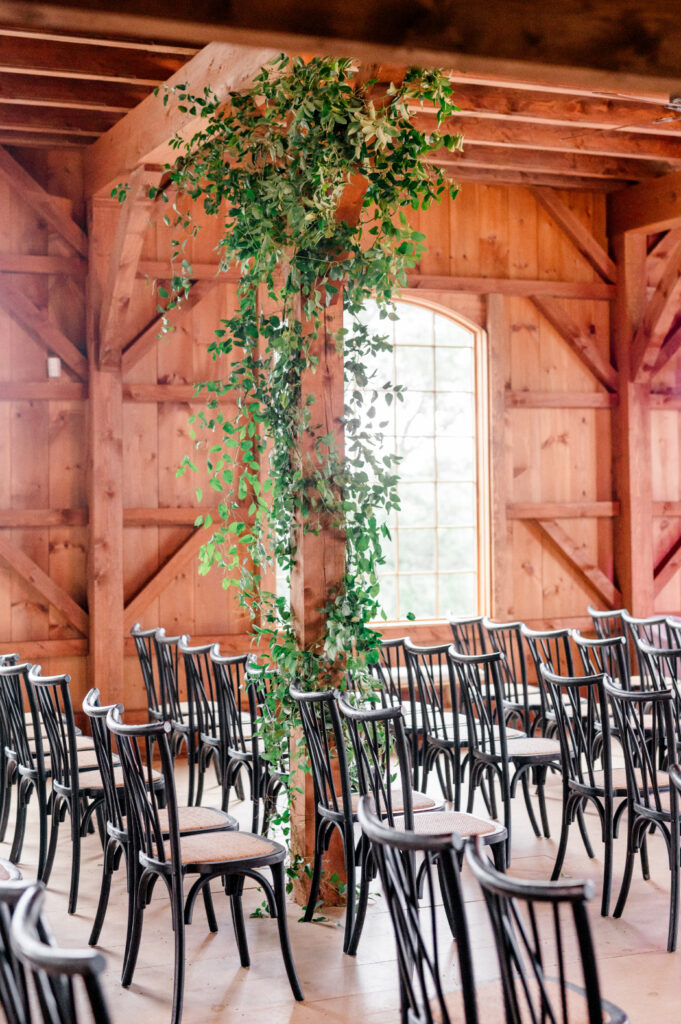 wedding ceremony set up with black chairs and greenery at willow hill