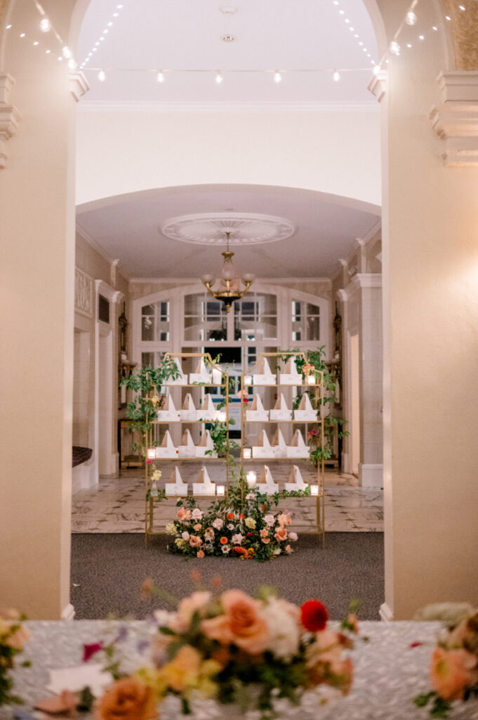 Escort card display featuring delicate calligraphy and fresh floral accents 