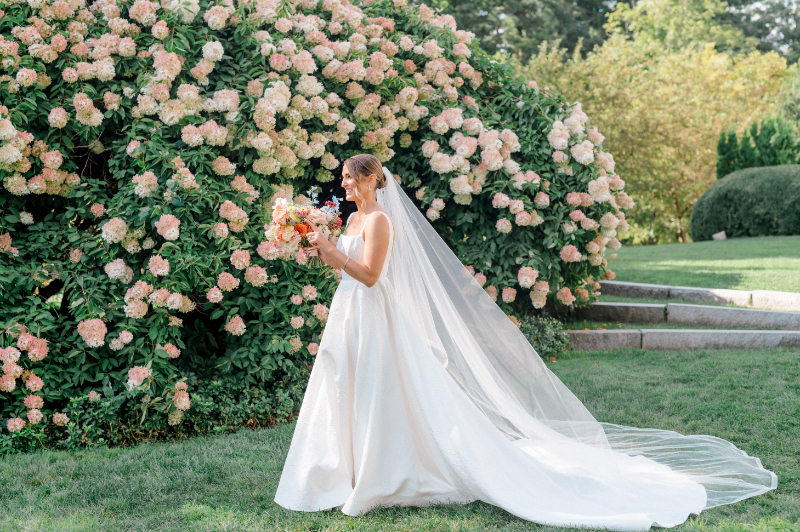 Bride beside a floral bush in the garden during her wedding at the Wadsworth Mansion 