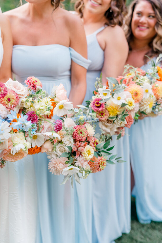 Bridesmaids in their soft neutral toned dressed with white and blush florals and flowing greenery