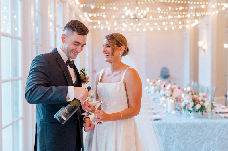 Bride and groom popping a bottle of champagne on their wedding day