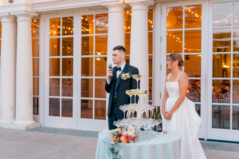 Bride and groom sharing a speech before toasting from the champagne tower 