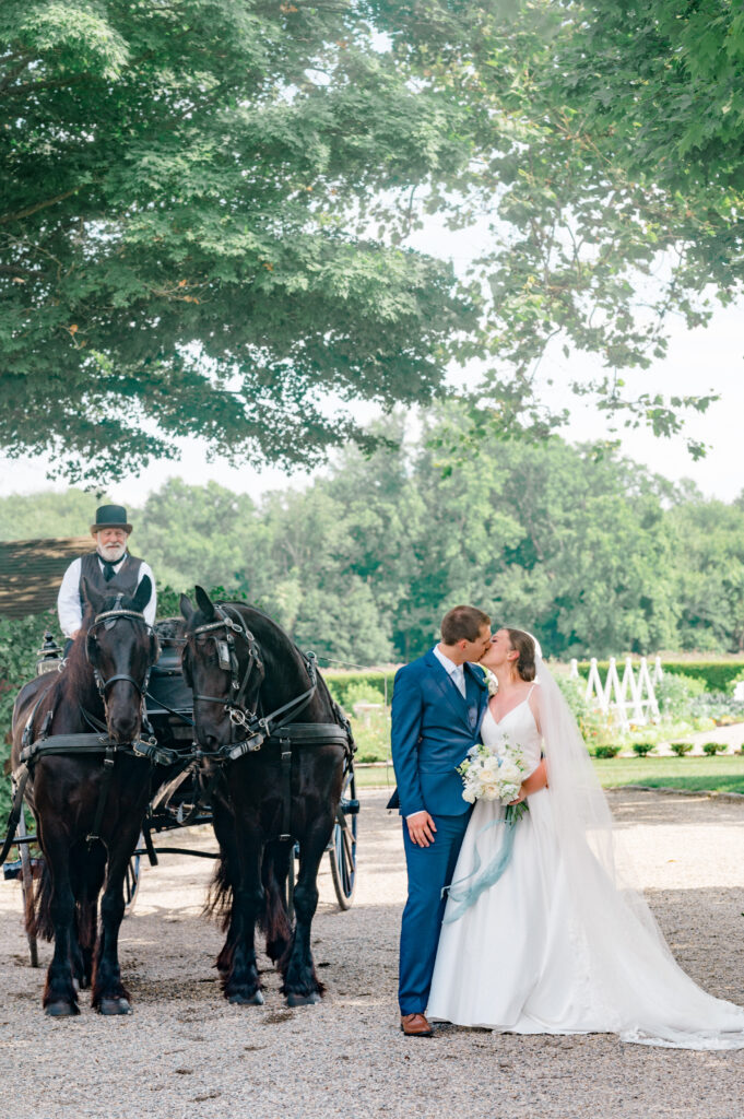 Romantic fine art wedding photo of bride and groom kissing with horses and trees at Smith Farm Gardens.