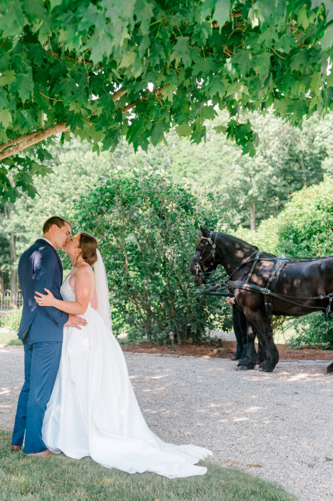 Light and airy couple’s portrait under lush greenery with elegant black carriage at Smith Farm Gardens, CT.