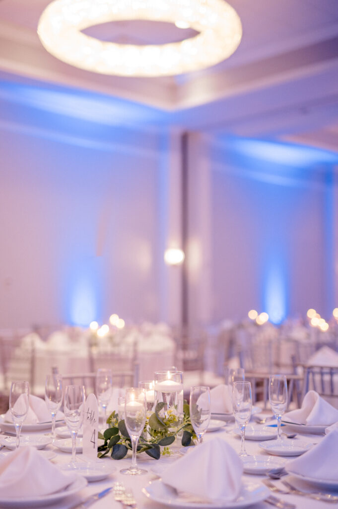 Elegant candlelit wedding reception tables with greenery runners and soft uplighting at Newport Harbor Island Resort.