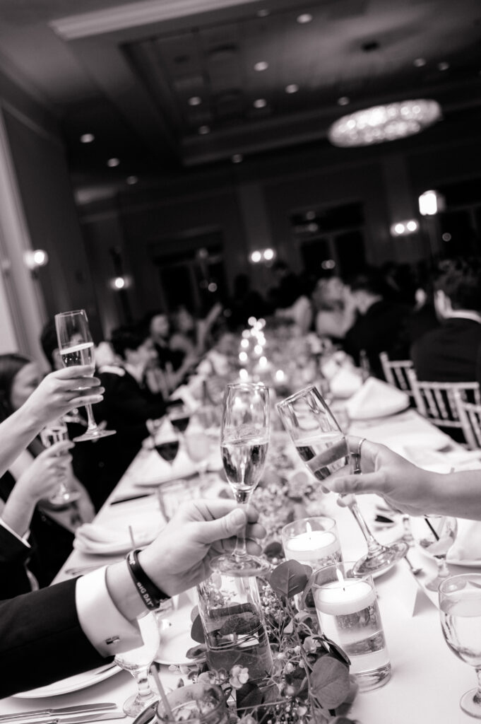 Black-and-white photo of guests making a celebratory toast during reception at Newport Harbor Island wedding.