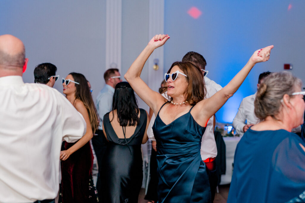 Wedding guest dancing with joy in heart sunglasses during a high-energy Newport Harbor Island Resort wedding party.