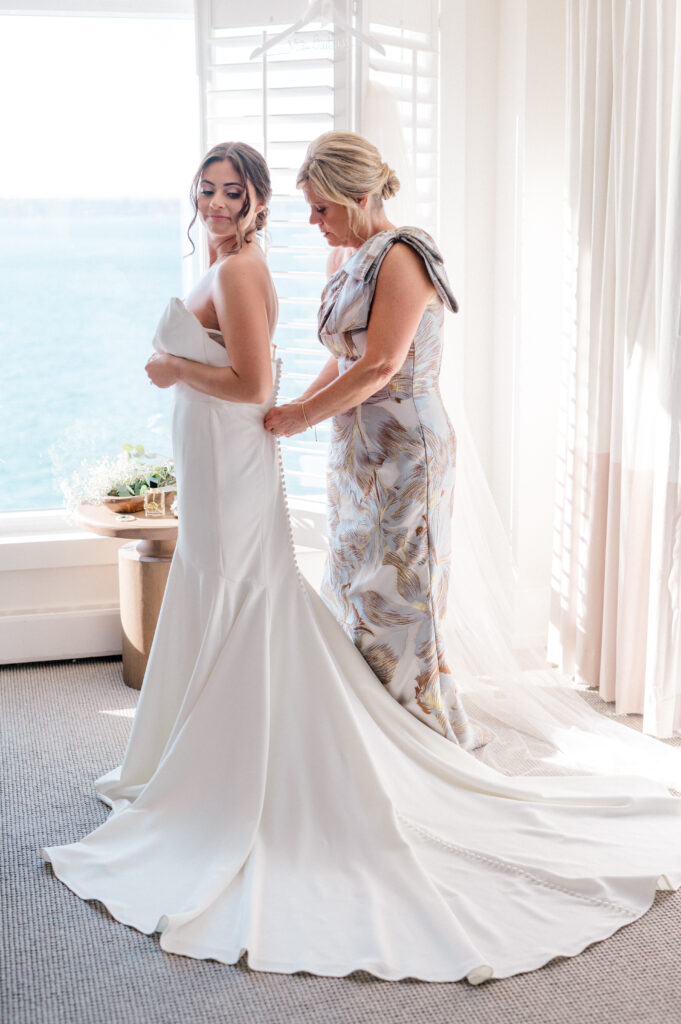 Bride and mother sharing a quiet moment as bride finishes dressing, part of Connecticut wedding photography timeline captured by Jennifer Nichole.