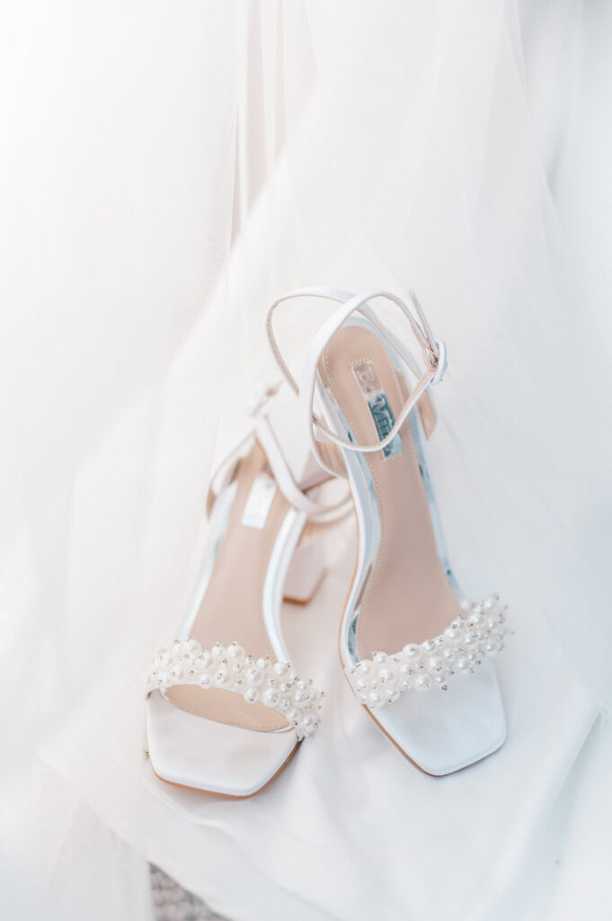 Close-up of white satin bridal heels with pearl embellishments on veil during Newport Harbor Island wedding prep