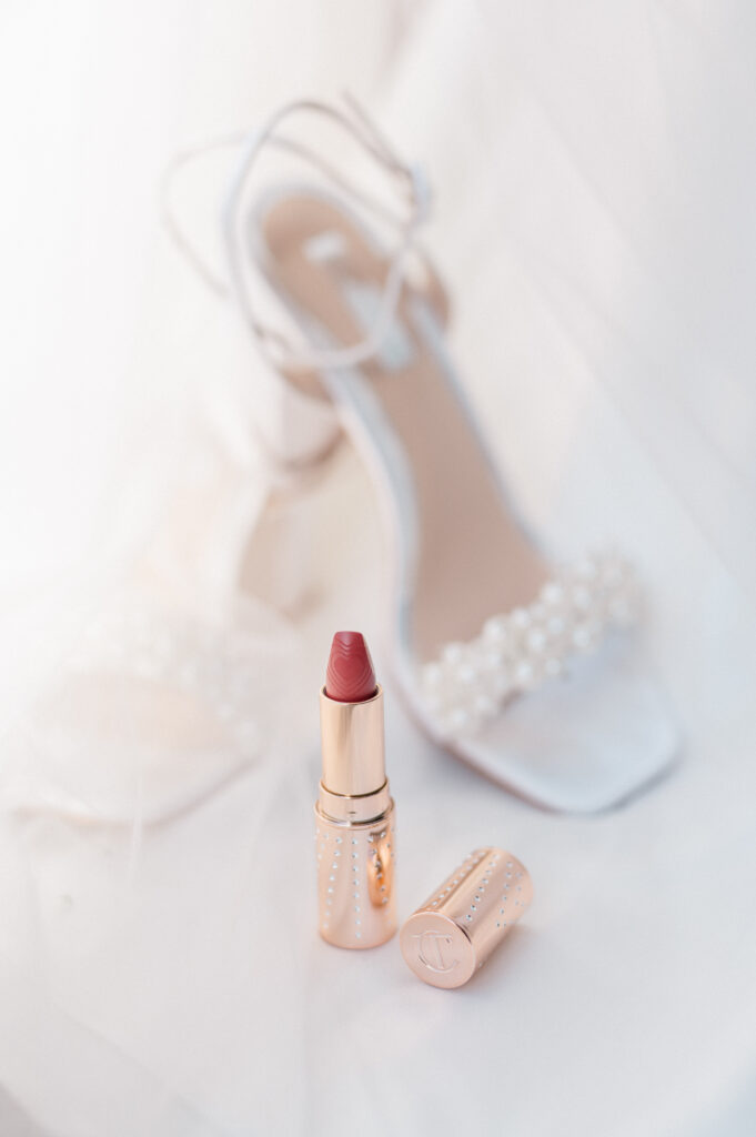 Rose gold Charlotte Tilbury lipstick with pearl-studded bridal heels in soft natural light at Newport Harbor Island wedding