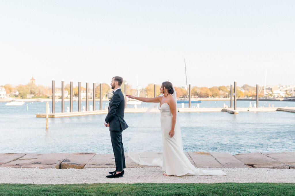 Bride approaching groom from behind for their emotional first look along the waterfront at Newport Harbor Island Resort.