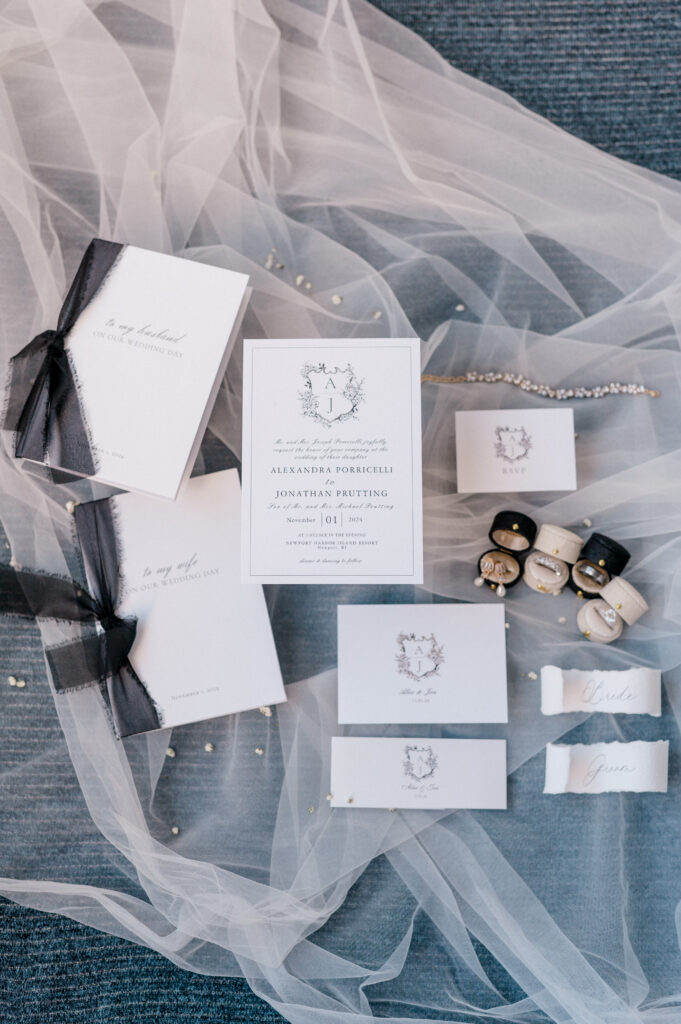 Elegant wedding stationery suite styled with vow books, RSVP cards, and veil for a Newport Harbor Island wedding