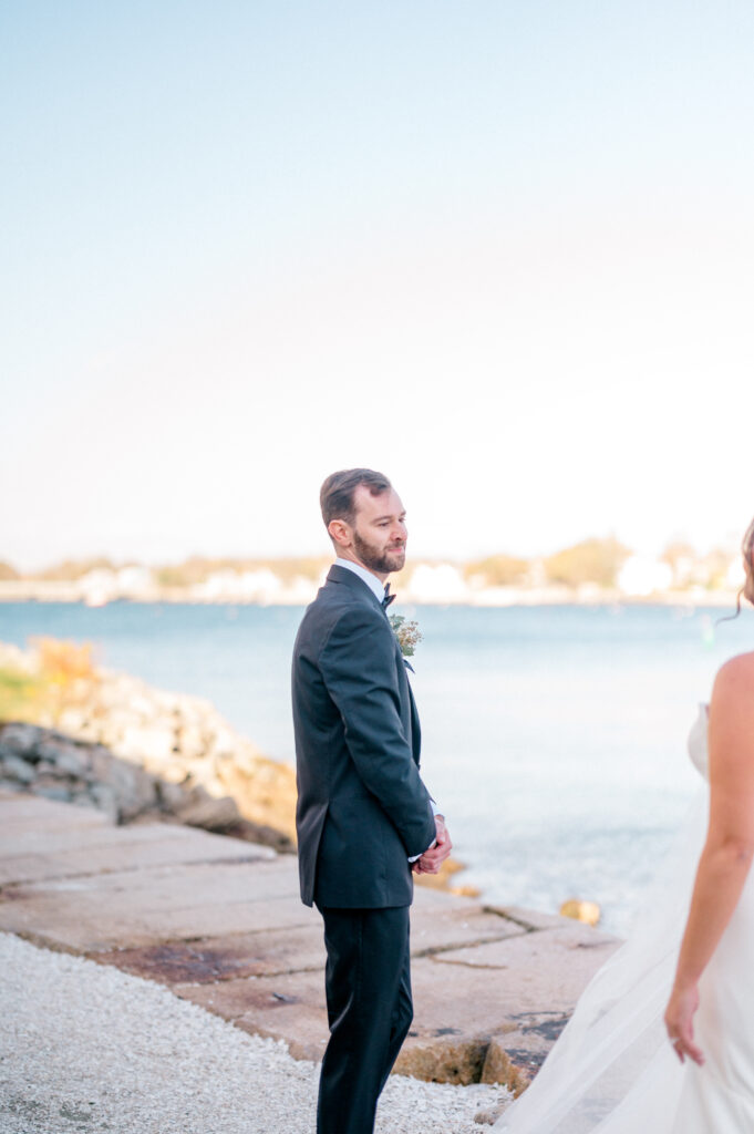Emotional groom gazing at his bride for the first time during their private first look along the water in Newport.