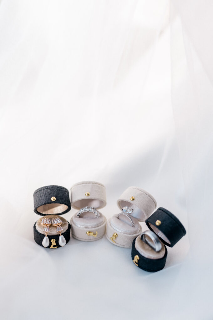 Elegant velvet ring boxes with wedding rings and earrings styled against a soft white veil, photographed by Jennifer Nichole & Co.