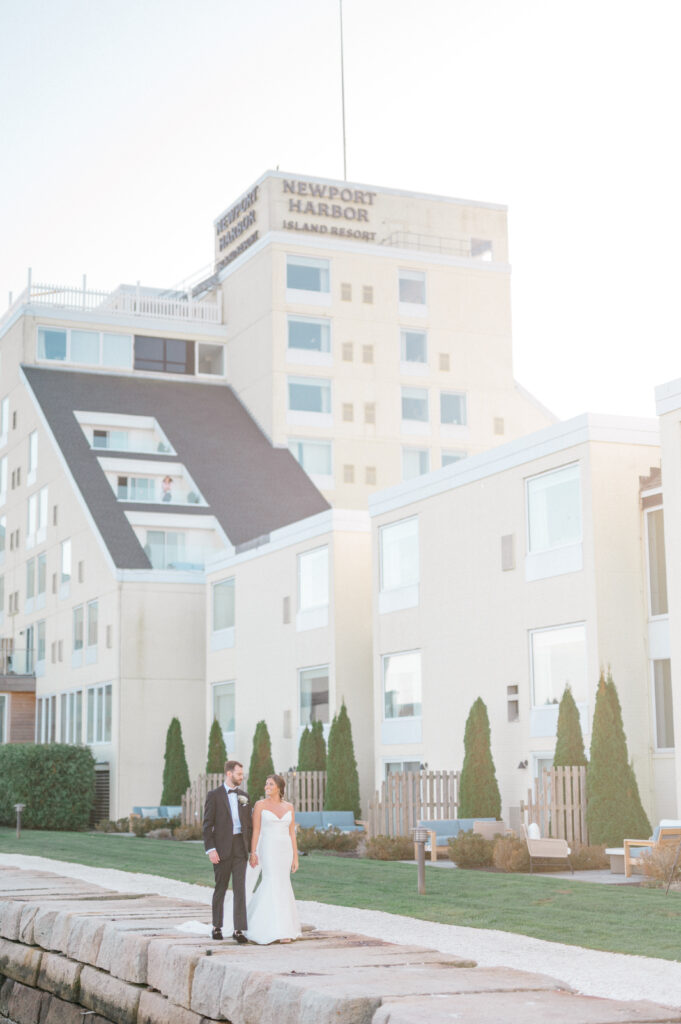 Newlyweds celebrating with bouquet and pointed hands at golden hour by the water in Newport