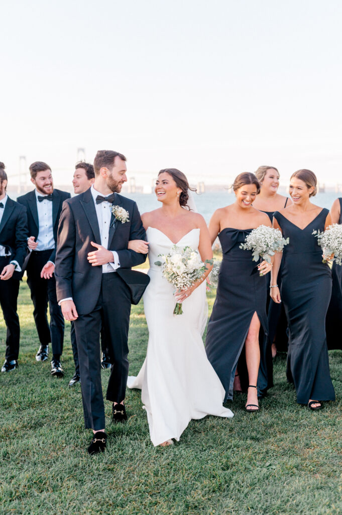 Bride and group walking arm in arm with the wedding party trailing behind.