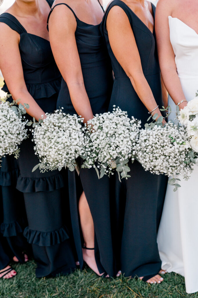 Closeup of bridesmaids holding large round bouquets of babys breath.